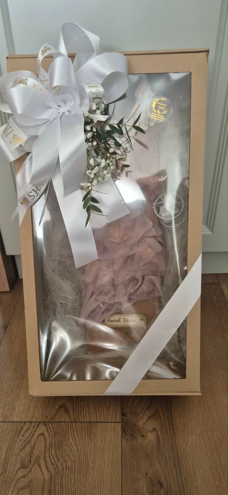 Luxury gift box with white ribbon bow and babys breath flowers on wooden floor