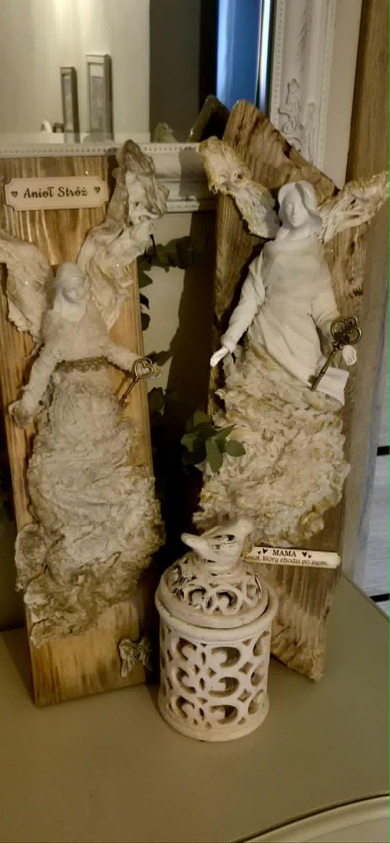 Decorative wooden display with carved angel figurines and ornamental pieces labeled Ancient Stories and Mama